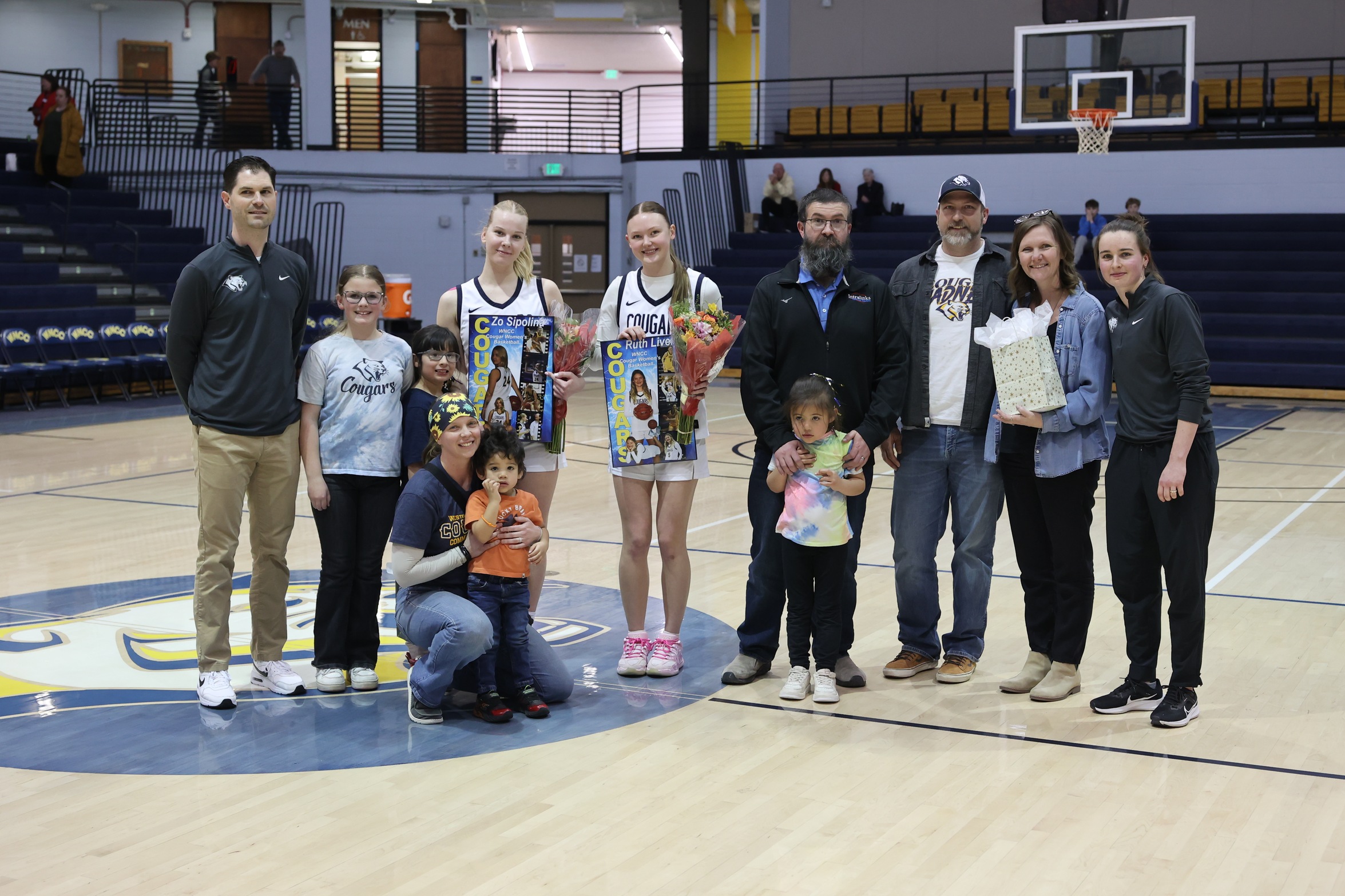 Ruth Lively and Zo Sipolina with their families and coaches during the graduating players recognition between the games on Wednesday.